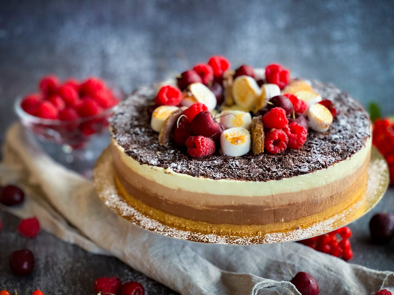 Delicious triple-layer cheesecake topped with fresh berries and chocolate shavings, ideal for celebrations.